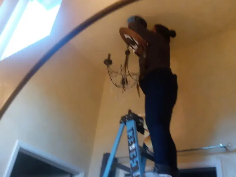 Electrician installing a chandelier in a Canyon residence